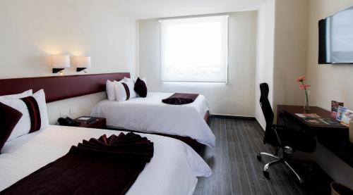 a hotel room with two beds and a flat screen tv at Mision Puebla Angelopolis in Puebla