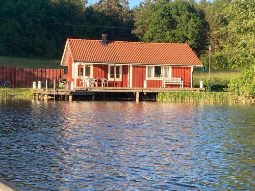 a red house on a dock on a body of water at Sjöstugan in Söderköping