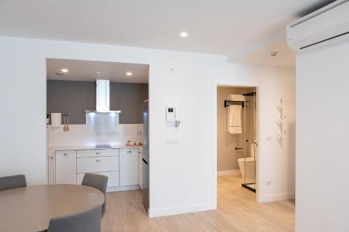 a kitchen and dining room with white cabinets and a table at CONCHEIROS 5 APARTAMENTOS TURISTICOS in Santiago de Compostela
