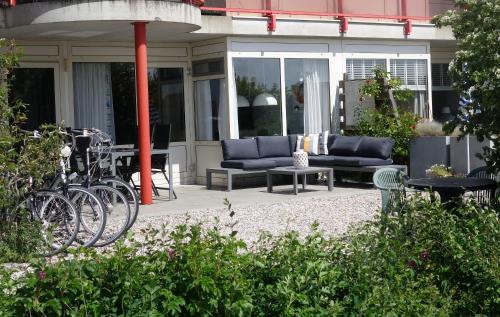 a patio with a couch and a table and chairs at Duinzicht, ruim appartement met terras op de begane grond nabij strand in Buren