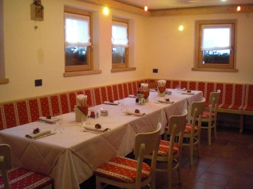 a dining room with white tables and chairs and windows at Albergo Riglarhaus in Sauris