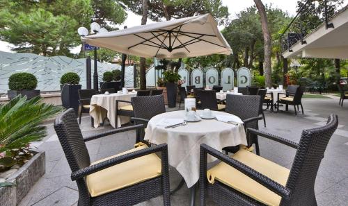 un restaurante con mesas, sillas y sombrilla en Hotel Globus, Sure Hotel Collection by Best Western, en Milano Marittima