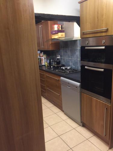 a kitchen with wooden cabinets and a black stove top oven at Beautiful Bungalow Home Droitwich SPA in Droitwich