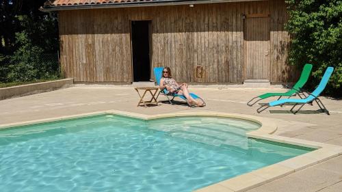 a woman sitting in a chair next to a swimming pool at L´Aveneau in Le Retail