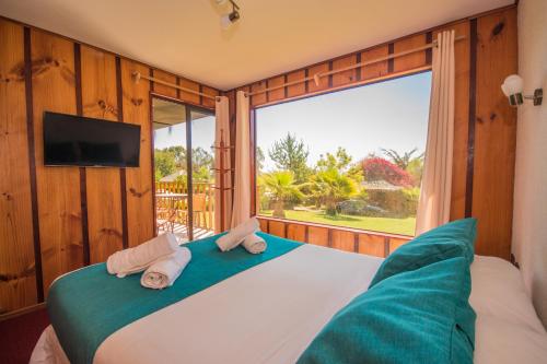 Un dormitorio con una cama y una ventana grande. en Pao Pao Lodge Algarrobo, en Algarrobo