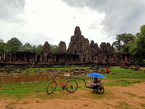 a bike parked in front of a temple with a blue umbrella at Kakrona Pouk Homestay in Siem Reap
