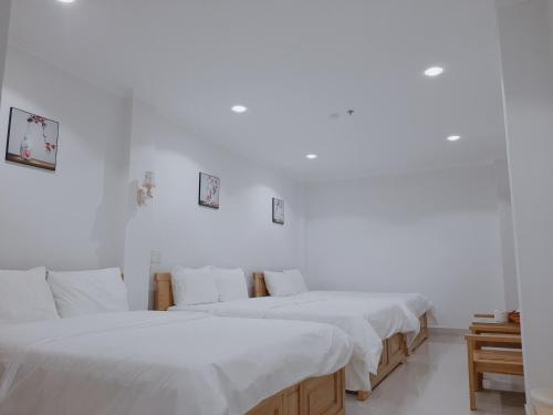 a group of three beds in a white room at Minh Manh Hotel 2 in Pleiku