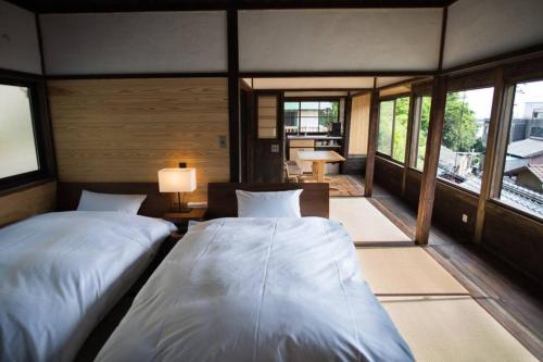 two beds in a room with windows at 鞆猫庵 Tomo Nyahn in Fukuyama