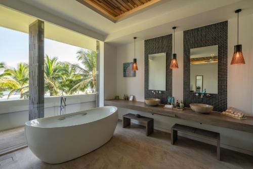 a bathroom with a tub and two sinks and mirrors at Mia Resort Nha Trang in Nha Trang