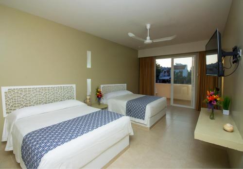 una camera d'albergo con due letti e una televisione di Hotel Huatulco Máxico a Santa Cruz Huatulco