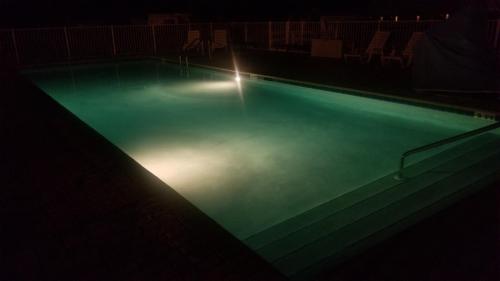 a swimming pool at night with lights in it at Deerwood Inn & Madison Campground in Madison