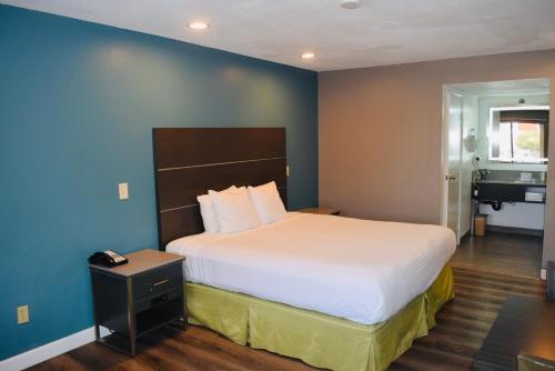 a bedroom with a bed and a blue wall at Hotel Milagro in Chula Vista