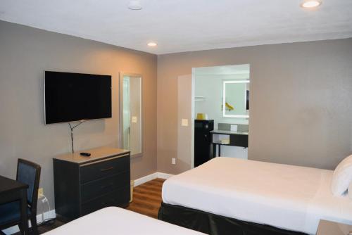 a hotel room with two beds and a flat screen tv at Hotel Milagro in Chula Vista