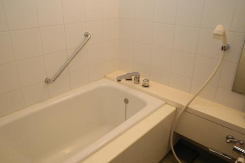 a bathroom with a white tub and a sink at Nishiizu Crystal View Hotel in Nishiizu