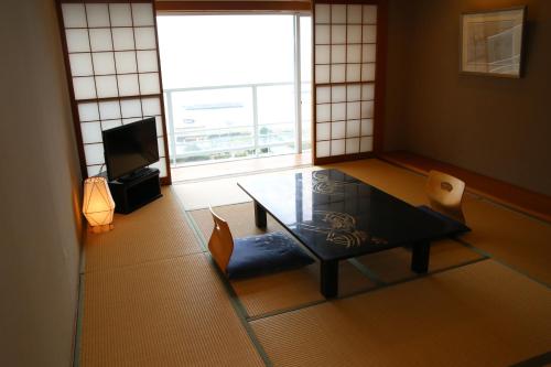 a living room with a table and a television at Nishiizu Crystal View Hotel in Nishiizu