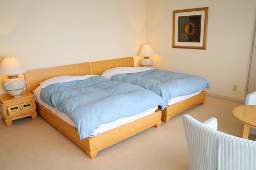 a bedroom with two beds and a table and two lamps at Nishiizu Crystal View Hotel in Nishiizu