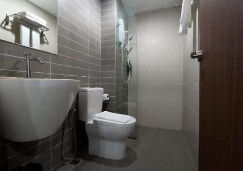 a bathroom with a white toilet and a sink at Regatta Suites Hotel at Kozi Square Kuching in Kuching