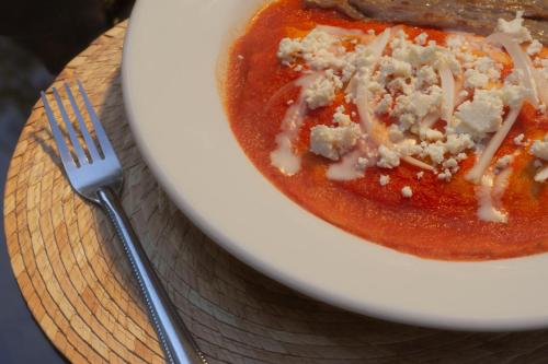 a bowl of tomato soup with cheese and a fork at NaNa Vida Hotel Oaxaca in Oaxaca City