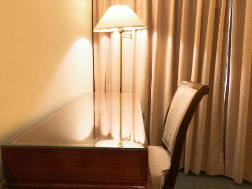 a desk with a lamp and a chair next to a curtain at Moonlight Hotel in Hsinchu City