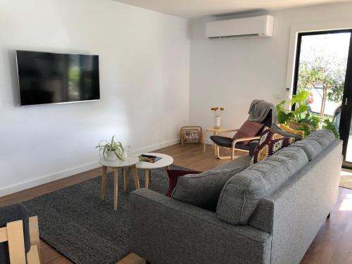 a living room with a gray couch and a tv at Oak Lane Guest House & Farm Stay in Whorouly