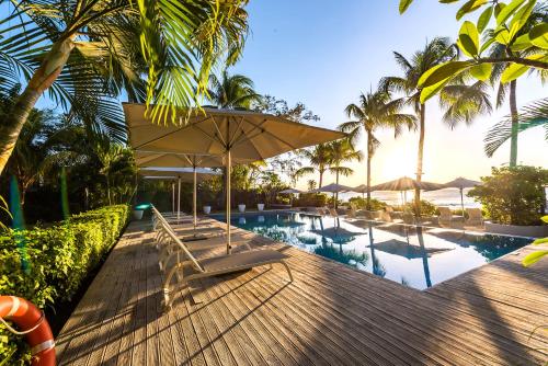 ein Resort mit einem Pool und einer Terrasse mit Stühlen und einem Sonnenschirm in der Unterkunft Mon Choisy Beach R. in Mont Choisy