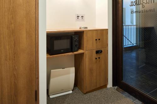 a room with a microwave and a tv on a shelf at mizuka Imaizumi 2 - unmanned hotel - in Fukuoka