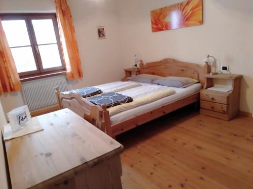 Un dormitorio con una gran cama de madera y una mesa. en Schornhof, en Aldino