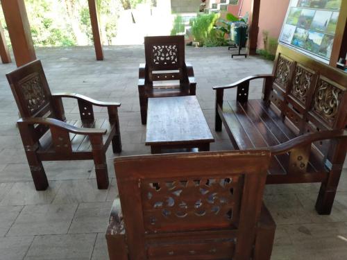 a group of wooden chairs and tables on a patio at Bina Karya Guesthouse Syariah in Bantul