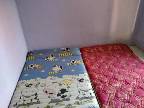 a bed with a sheet with cows on it at Bina Karya Guesthouse Syariah in Bantul