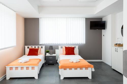 a bedroom with two beds with orange pillows at Kostovski Rooms-near E75 to Greece in Veles