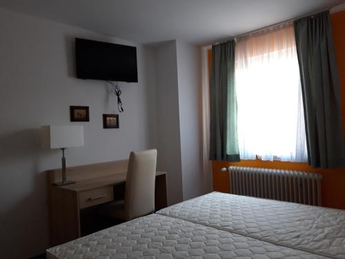 a bedroom with a bed and a desk and a window at Cafe Restaurant Rohan in Ettenheim