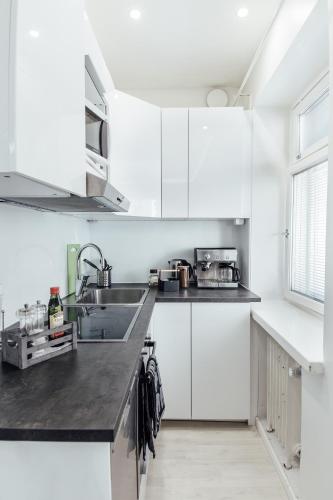 una cucina bianca con mobili bianchi e un lavandino di Sailor`s Apartment a Helsinki