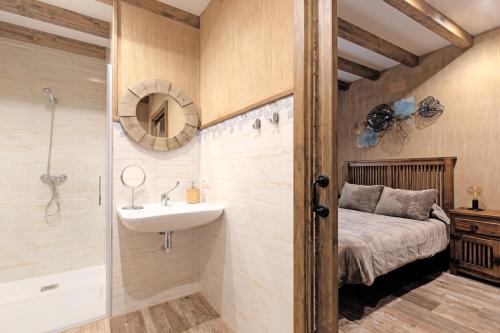 a bathroom with a sink and a shower and a bed at El Rincón de la Iglesia in Cabezuela del Valle