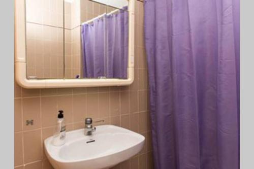 a bathroom with a sink and a purple shower curtain at GRAN VISTA in Santa Pola