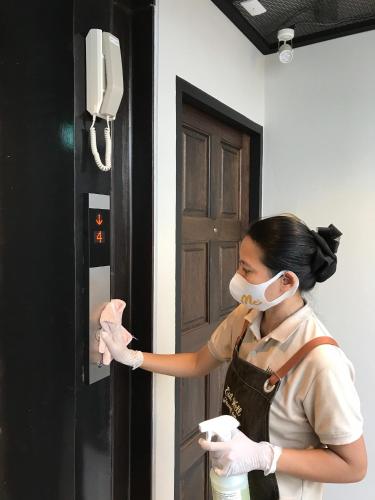 a woman wearing a mask and gloves and a door at FOODOTEL in Bangkok