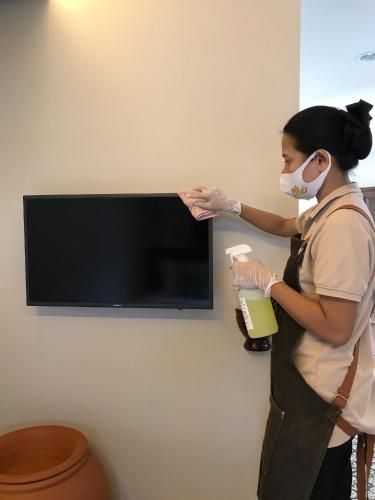 a woman wearing a mask and gloves holding a bottle at FOODOTEL in Bangkok
