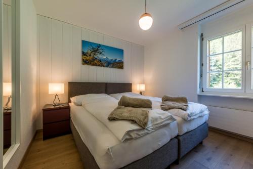 a bedroom with a large bed with two pillows on it at Montela Hotel & Resort - Casa Antares in Saas-Grund