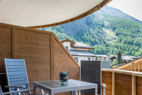 a table and chairs on a balcony with a mountain at Montela Hotel & Resort - Casa Antares in Saas-Grund