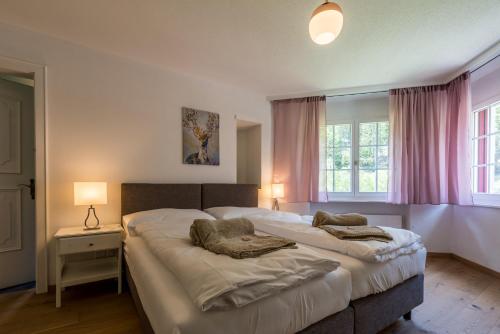 two beds in a bedroom with pink curtains at Montela Hotel & Resort - Haus Antares in Saas-Grund