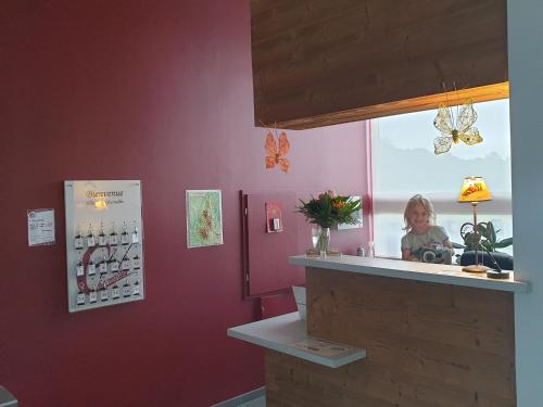 a little girl is standing at a counter in a restaurant at Hôtel Les Charmilles in Besse-et-Saint-Anastaise