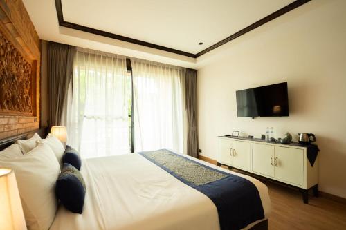 a hotel room with a bed and a flat screen tv at Phor Liang Meun Terracotta Arts in Chiang Mai