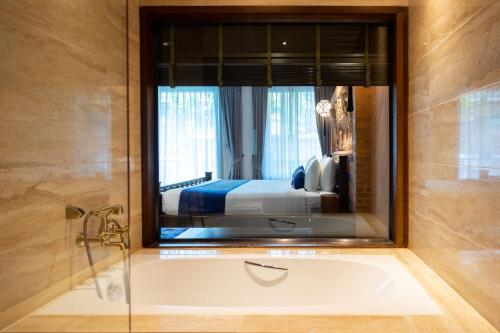 a bathroom with a bath tub and a bedroom at Phor Liang Meun Terracotta Arts in Chiang Mai