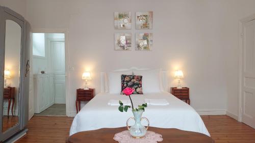 una camera da letto con un letto bianco e un vaso con un fiore all'interno di La Maison Serrurier - Chambres d’hôtes a Morlaix
