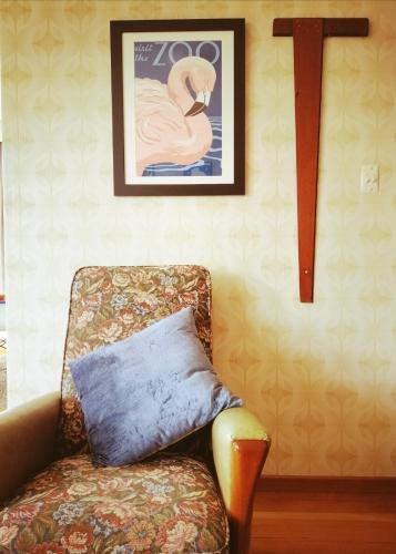 a chair with a pillow and a picture of a swan at Super Central Cosy Greytown House with Garage in Greytown