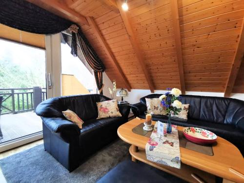 una sala de estar con sofás de cuero negro y techo de madera. en Ferienhaus Wieke, en Wiesmoor