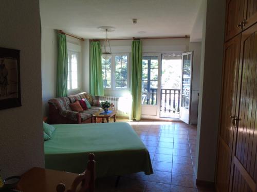 salon z łóżkiem, kanapą i oknami w obiekcie Apartamentos Turísticos Cumbres Verdes w mieście La Zubia