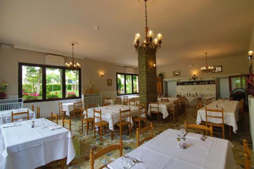 restauracja z białymi stołami i krzesłami oraz żyrandolem w obiekcie Hotel Falco D'Oro w mieście Tolè