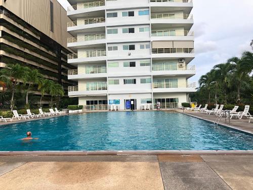 a person swimming in a swimming pool in front of a building at View Talay 6 Pattaya Beach Apartment by Honey in Pattaya