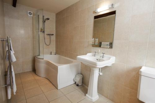 a bathroom with a tub and a sink and a shower at Church Farm Lodge in Harrington