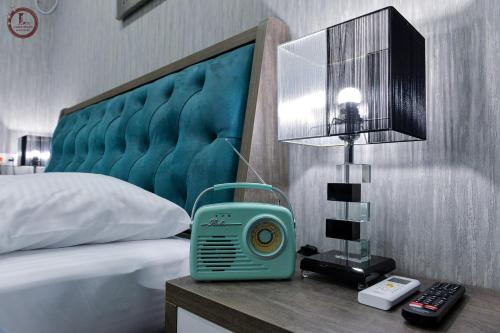 a bedroom with a bed with a blue clock on a night stand at SULIKO Apartment in Kutaisi